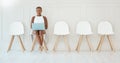 Young focused African american businesswoman working on laptop while waiting for interview sitting on a chair against a Royalty Free Stock Photo