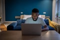 Young focused African American man freelancer working on laptop until late hours at home Royalty Free Stock Photo
