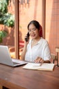 A young focused Asian woman is using a calculator while talking on the phone, working remotely Royalty Free Stock Photo
