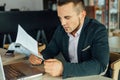 Young focused businessman sitting in cafÃÂ© with laptop and analy