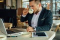 Young focused businessman sitting in cafÃÂ©, working on his lapto