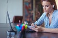 Young focused businesswoman making notes at laptop