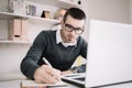 Young focused employee writing documents on office desk