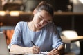 Young focused female sitting at table handwriting in notebook Royalty Free Stock Photo