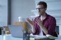 Young focused german man in glasses and casual clothes participating in virtual online meeting