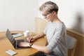 Young focused hipster millennial female working with laptop in cafe interior, close-up side view