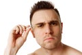 Young focused man with short brunette hair with tweezers looking at camera against white studio background. Royalty Free Stock Photo