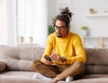 Young focused serious african american man relaxing at home with smartphone, surfing internet