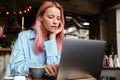 Young focused woman with pink hair working with laptop in cafe Royalty Free Stock Photo