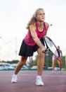 Young forcefully teenage girl playing tennis close to net on court