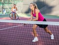 Young forcefully teenage girl playing tennis close to net on court