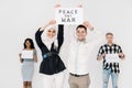 Young four people activists of different nationalities hold slogans for peace, no war and earth protection. Muslim girl Royalty Free Stock Photo