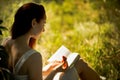 Young foxy haired woman reading book in nature.