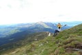 Young free female tourist wearing yellow jacket sitting in Appenine mountains.