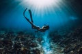 Young freediver woman with fins glides and amazing sun rays. Freediving underwater in sea