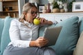 Young freelance business woman working at home on tablet as product strategy expert. Female expatriate remote work on internet on Royalty Free Stock Photo