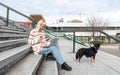 Young freelance expat woman sitting on the stairs of office building drinking coffee and working on laptop computer with her dog Royalty Free Stock Photo