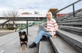 Young freelance expat woman sitting on the stairs of office building drinking coffee and working on laptop computer with her dog Royalty Free Stock Photo