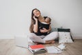 Mother working at home with baby in ergo backpack