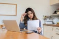 Young Freelance Woman Feeling Stressed While Working from Home, Analyzing Documents at Kitchen Table with Laptop Royalty Free Stock Photo
