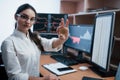 Young freelancer in eyewear. Beautiful woman holding bitcoin in hands while sitting in modern office with many monitors Royalty Free Stock Photo