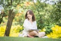 Young freelancer with laptop and headphones in a green park. Cheerful modern woman sitting outdoors in the park on grass and using Royalty Free Stock Photo