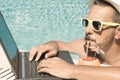 Young freelancer working on vacation next to the swimming pool Royalty Free Stock Photo