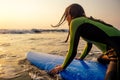 Young freelancing woman in a wetsuit swimming over surfboard in the water at beach.surfer girl relaxing in paradise Royalty Free Stock Photo