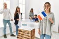 Young french voter woman smiling happy holding france flag standing by ballot at vote center