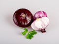 Red flat onion in the skin and half an onion with leaves of fresh young parsley, isolated on a white background