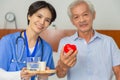 Young friendly asian female caregiver look at camera to happy senior man in nursing home Royalty Free Stock Photo