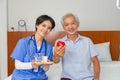 Young friendly asian female caregiver look at camera to happy senior man in nursing home Royalty Free Stock Photo