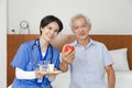 Young friendly asian female caregiver look at camera to happy senior man in nursing home Royalty Free Stock Photo