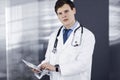 Young friendly doctor is checking some information on his computer tablet. Portrait of a professional physician at work