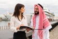 Young friendly europian businesswoman explaning contract details to arab man during meeting in port Royalty Free Stock Photo