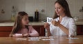 Mother tests knowledge of multiplication showing flashcards to preschool daughter