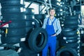 Young friendly mechanic man working with car tires in workshop Royalty Free Stock Photo