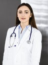 Young friendly woman-doctor is looking at camera with a smile, while she is standing in a cabinet. Professional Royalty Free Stock Photo