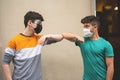 Young friends bump their elbows to greet in time covid-19. They use the mask to defend themselves from the coronavirus. Concept of