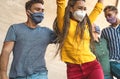 Young friends dancing together while wearing face mask outdoor - Happy people having fun in city after corona virus quarantine Royalty Free Stock Photo