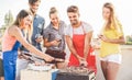 Young friends having barbecue party at sunset on house patio - Happy people doing bbq dinner outdoor cooking meat and drinking Royalty Free Stock Photo