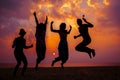 Young friends having fun on the beach and jumping against a backdrop of a sunset over the sea Royalty Free Stock Photo