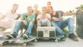 Young friends having fun at city skateboard pubblic park - Happy skaters laughing and watching videos on smartphone outdoor -