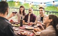 Young friends having fun drinking red wine at balcony penthouse dinner party - Happy people eating bbq food at fancy alternative Royalty Free Stock Photo