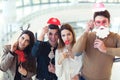 Young friends having fun holding winter artificial mustache