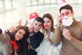 Young friends having fun holding winter artificial mustache