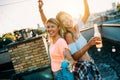 Young friends having fun at a rooftop party, playing the guitar, singing, dancing and drinking Royalty Free Stock Photo