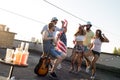Young friends having fun at a rooftop party, playing the guitar, singing, dancing and drinking Royalty Free Stock Photo