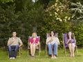 Young Friends With Icecreams On Deckchairs At Garden