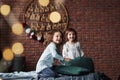 Young friends resting together. Little girls having fun on the bed with holiday interior at the background Royalty Free Stock Photo